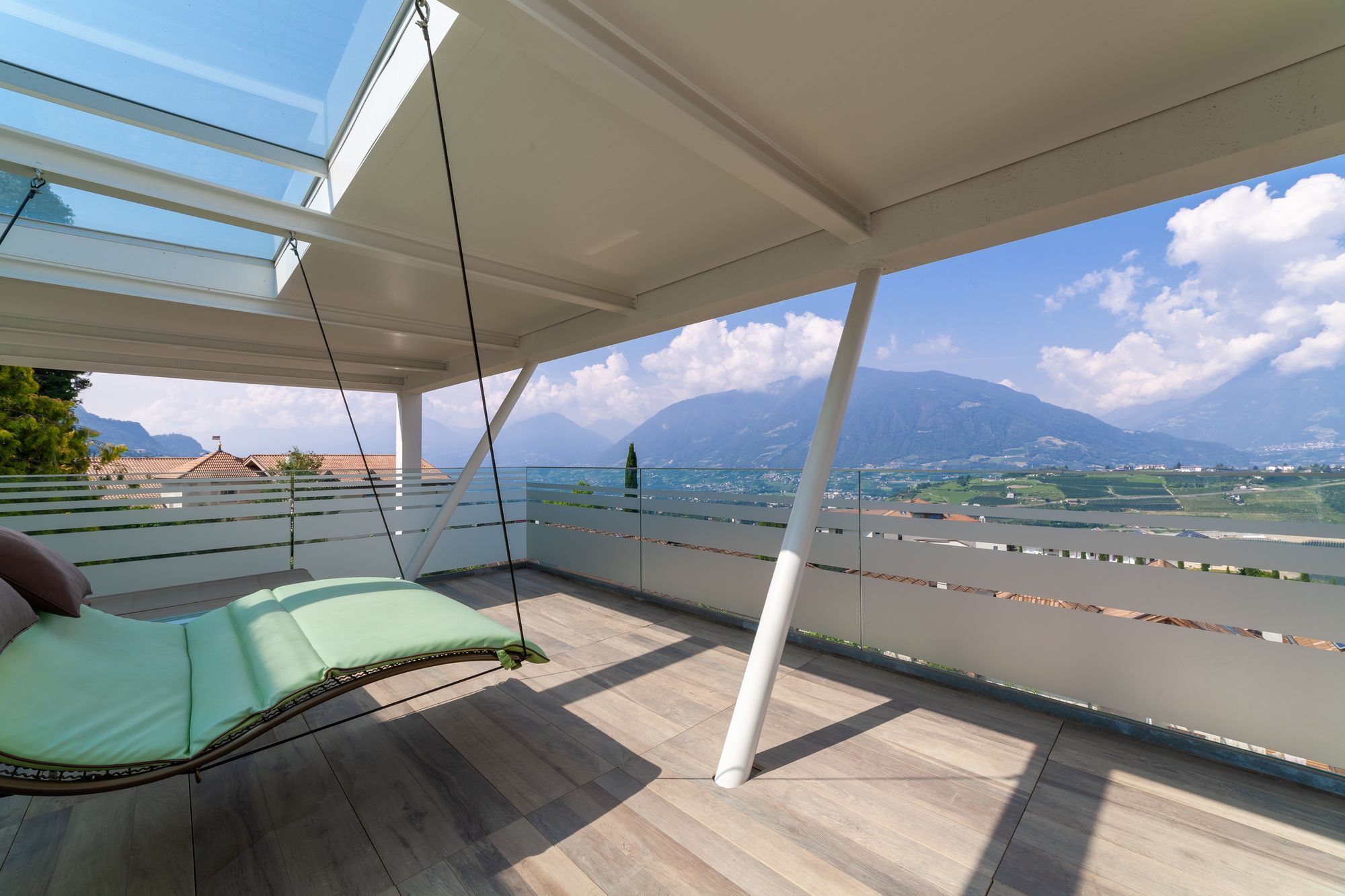 Überdachte Terrasse mit grüner Hängeliege und weitem Bergblick