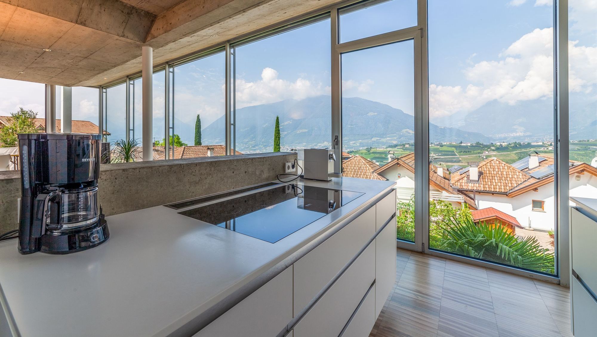 Moderne Küche mit Kochinsel und Panoramafenster, Blick auf Dächer und Berge