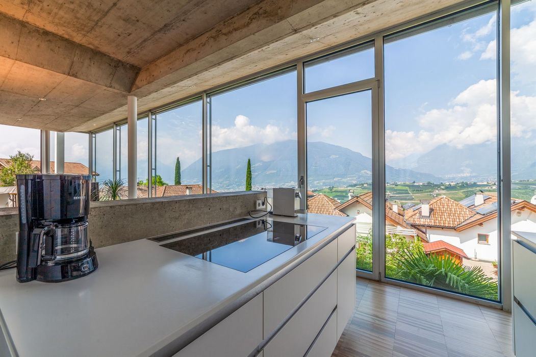 Moderne Küche mit Kochinsel und Panoramafenster, Blick auf Dächer und Berge