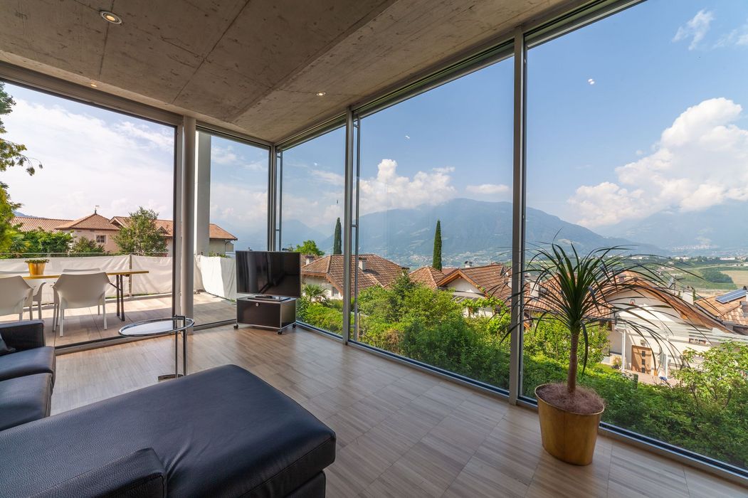 Helles Wohnzimmer mit bodentiefen Fenstern, Terrasse und Bergblick