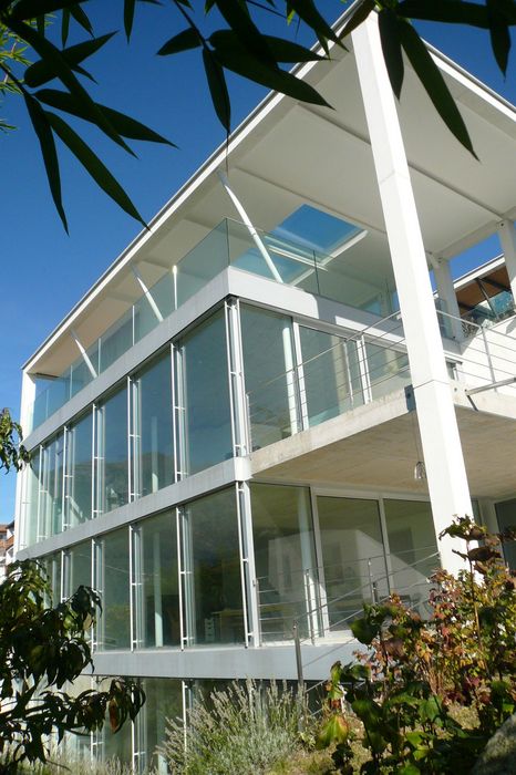 Moderner weißer Mehrfamilienbau mit großen Glasfronten und Balkonen vor blauem Himmel
