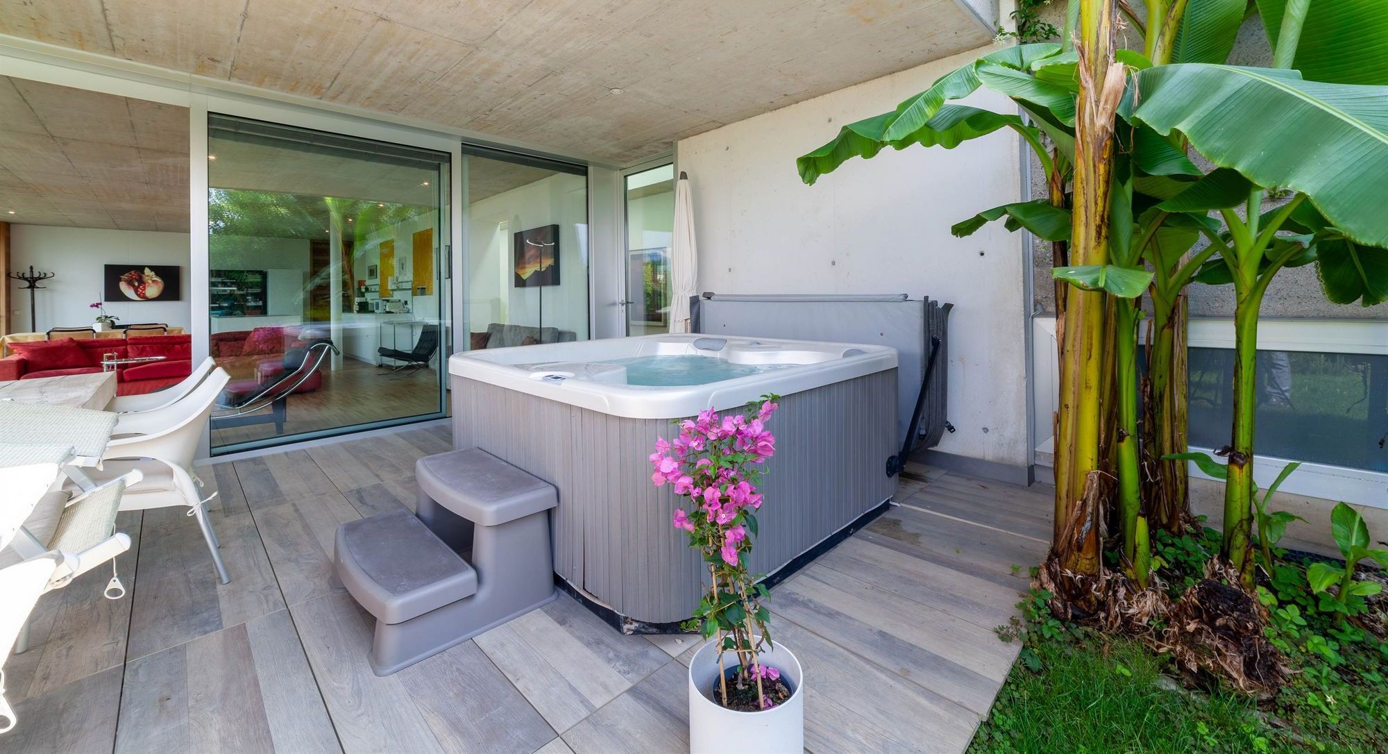 Terrasse mit Whirlpool, Sitzbereich und großen Bananenpflanzen
