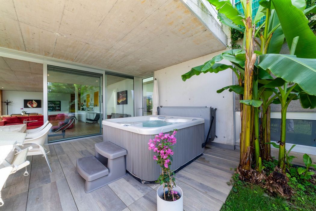 Terrasse mit Whirlpool, Sitzbereich und großen Bananenpflanzen