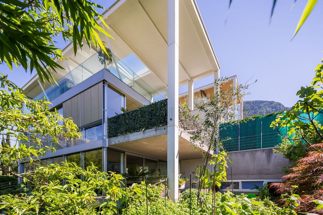 Modernes Glas-Haus mit Balkonen und üppiger Gartenbepflanzung